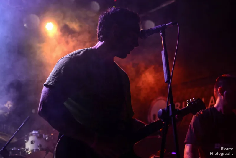 Guitarrista a contraluz entre humo naranja en Entriopia Fest