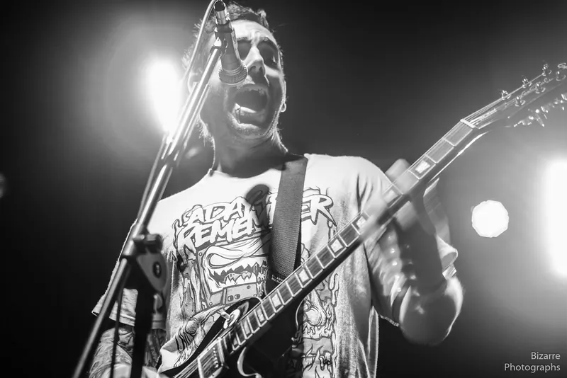 Guitarrista cantando con fuerza a contraluz en Entriopia Fest, en blanco y negro