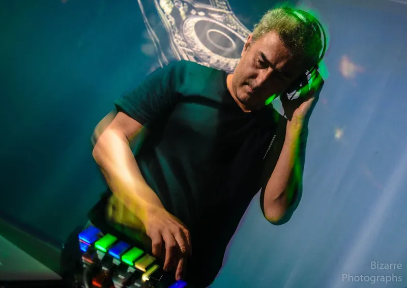 DJ con auriculares bajo luz verde y azul junto al controlador en The Spot